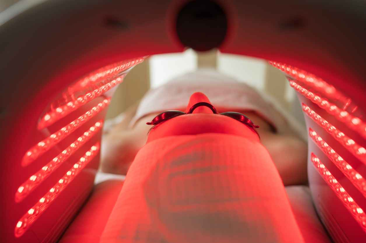 Client enjoying red light therapy administered by a skilled esthetician in a modern beauty clinic, enhancing skin health and rejuvenation